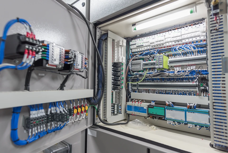 Intérieur d'armoire électrique industrielle ouverte montrant installation complexe de contrôle automatisé