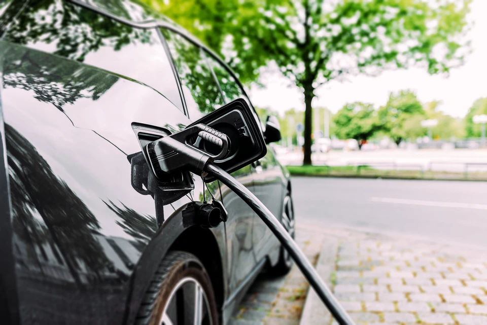 Scène extérieure urbaine avec véhicule électrique en charge sur voirie arborée