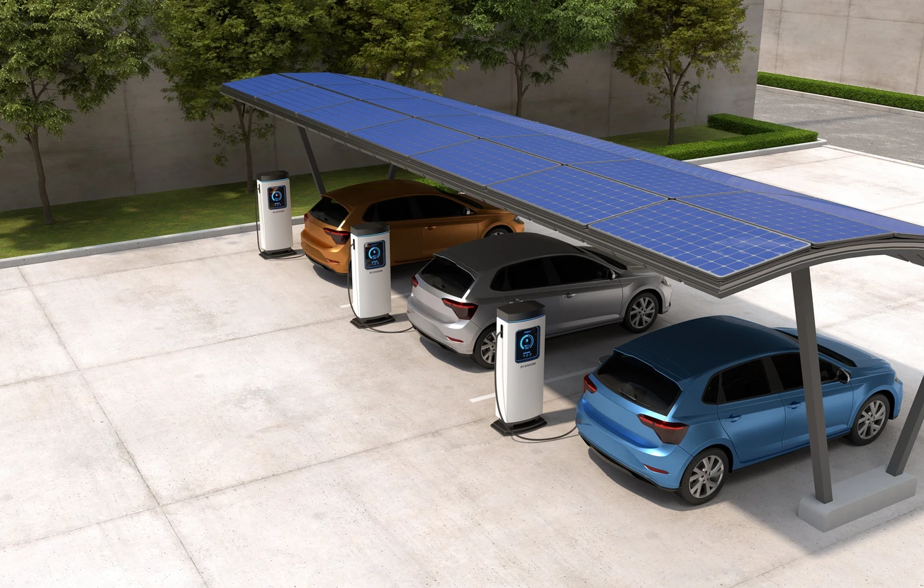 Station de recharge électrique extérieure avec trois véhicules électriques stationnés sous un auvent équipé de panneaux solaires photovoltaïques