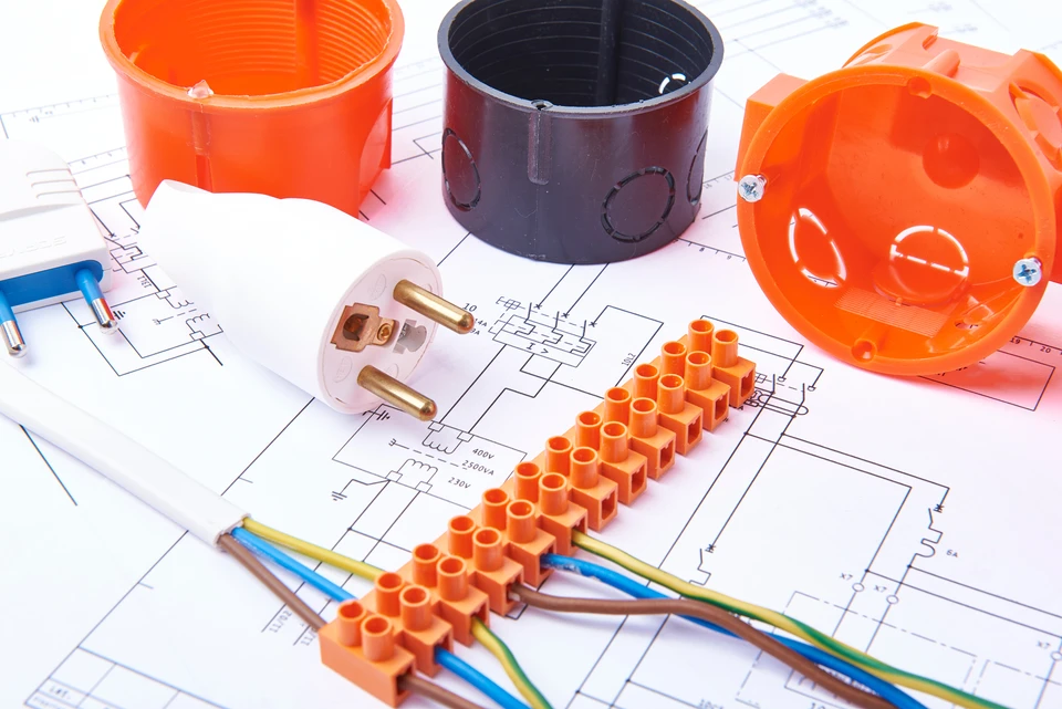 Espace de travail intérieur avec plans électriques techniques étalés sur surface blanche