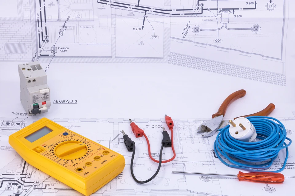 Gros plan sur une personne méconnaissable analysant une facture d'électricité avec une calculatrice, une ampoule et de l'argent sur un bureau