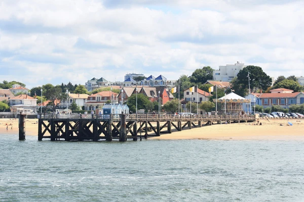 Photographie de la baie d'Arcachon avec ses dunes de sable blanc et ses pins maritimes en arrière-plan, capturant le paysage caractéristique de cette station balnéaire côtière girondaise. La composition doit montrer la beauté naturelle et reconnaissable du site pour illustrer clairement la zone géographique d'Arcachon, sans texte ni logo visible.