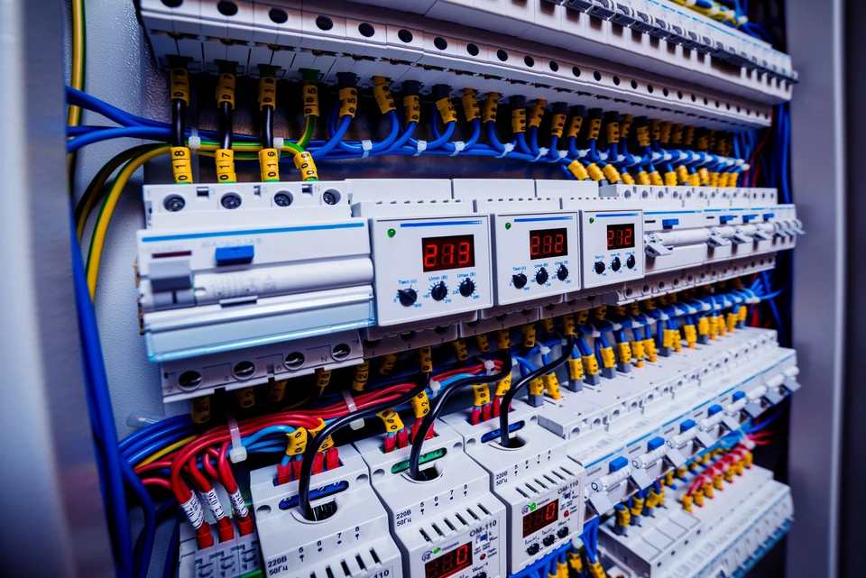 Technicien électricien en intervention extérieure utilisant un multimètre pour diagnostiquer un tableau électrique ouvert